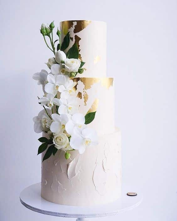 مدل کیک عروسی سه طبقه سفید و صورتی تزیین شده با ورق طلا و گل  