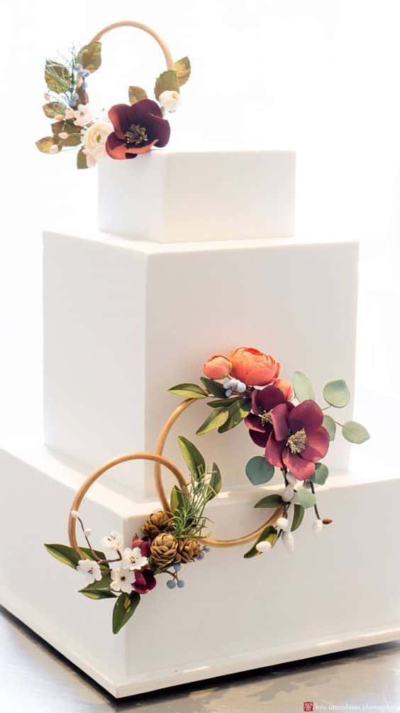 کیک عروسی مربعی سه طبقه تزیین شده با فوندانت و حلقه های گل  