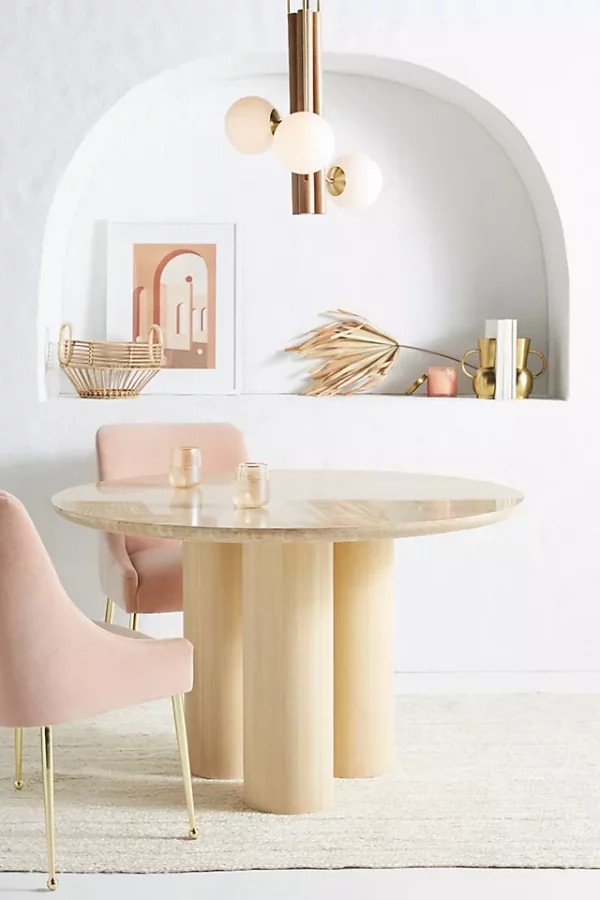 میز سنگی گرد با پایه های چوبی و صندلی های فلزی پارچه ای برای ناهارخوری
