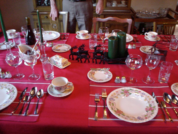 تزیین میز شام کریسمس به کمک شمع‌های سبز، رومیزی قرمز و گوزن‌ها 