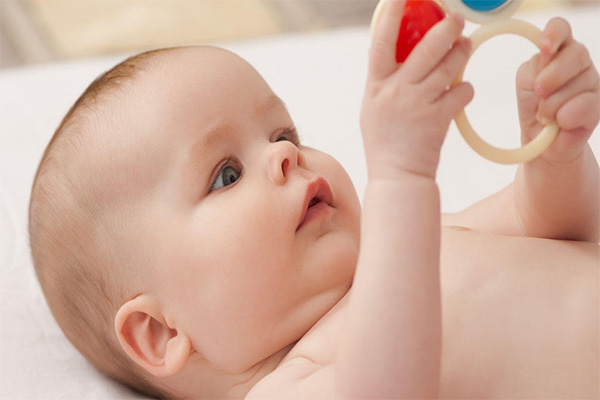 نوزاد سه ماهه اسباب بازی را در دست نگه می دارد