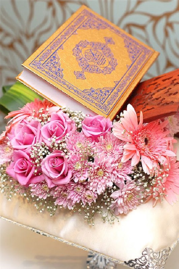 تزیین قرآن سفره عقد با قرار دادن دسته‌ای از گل در اطراف آن