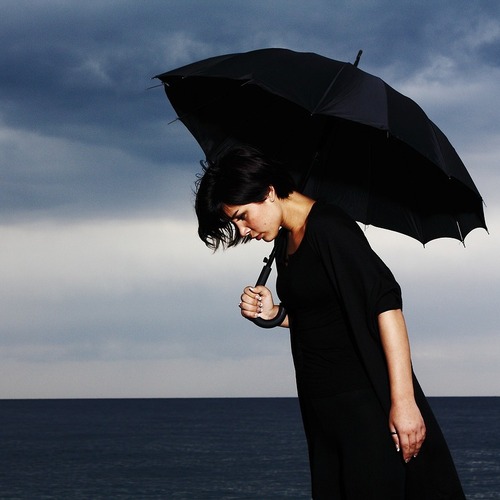 دختر غمگین با چتر کنار دریا